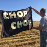 Photo of Larry Urbanksi in a grass field waving a Chop Chop baler flag