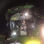 Photo of Derek Berger in a John Deere swather at night with the lights on