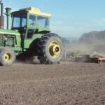 Historical photo of John Deere tractor doing field prep work for planting