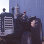 Historical photo of Berger family child on old Oliver tractor at shop