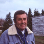 Historical photo of Ken Berger with barn and trees in background