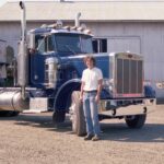 Historical photo of a summer operator in front of blue Peterbilt truck at the Hillsboro shop