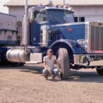 Historical photo of a summer operator in front of blue Peterbilt truck at the Hillsboro shop