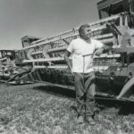 Historical photo of Ken Berger with John Deere harvester